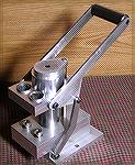 Third view of Jim Wolford's home built press. Steel shaft, links, and lever, with aluminum body. Mounts flat on a bench top in reduced footprint.Home built press.Bill Adair