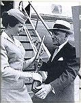 The State of gun control circa 1961.  This photo shows a man standing on the tarmac near a commercial aircraft while showing the flight attendant a double-barrel shotgun.  Can you imagine what would h