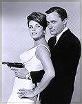 1960s television series Man from U.N.C.L.E. star Robert Vaughn posing with "suppressed" Walther P38K pistol and curvy guest star.